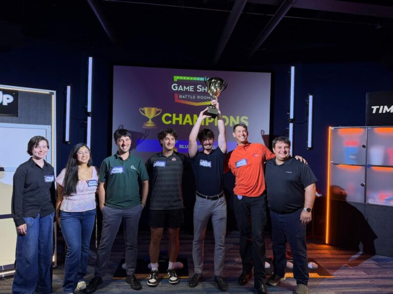 Phil Ratcliff with the rebel Financial team on stage holding up a champions trophy at a game show outing