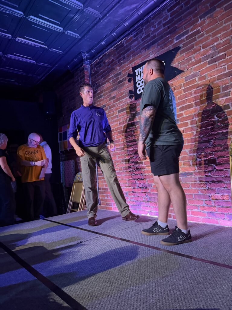 Phil Ratcliff mid-scene on stage at The Hashtag Comedy Co., July 2026