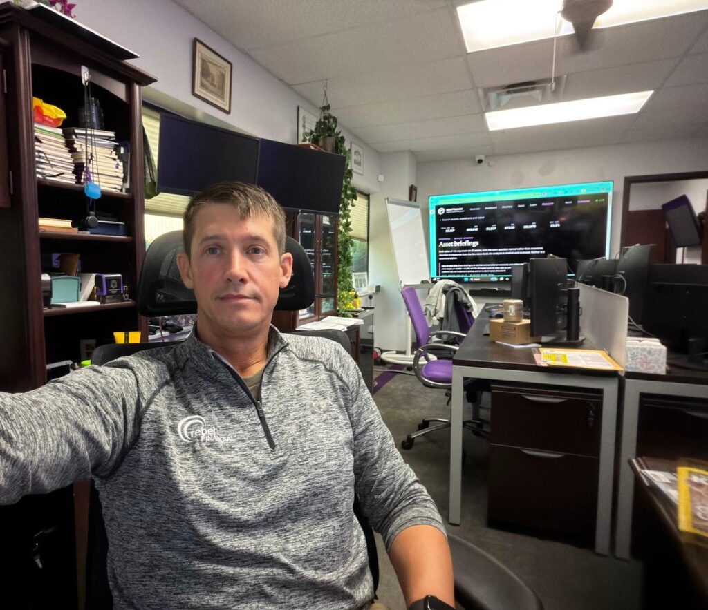 Phil Ratcliff at his desk in the rebel Financial office wearing a rebel pullover