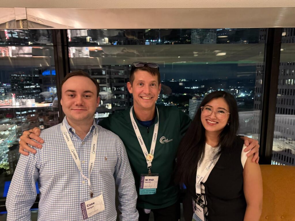 Phil Ratcliff with two rebel Financial teammates at the NAPFA conference in Atlanta, city skyline at night behind them