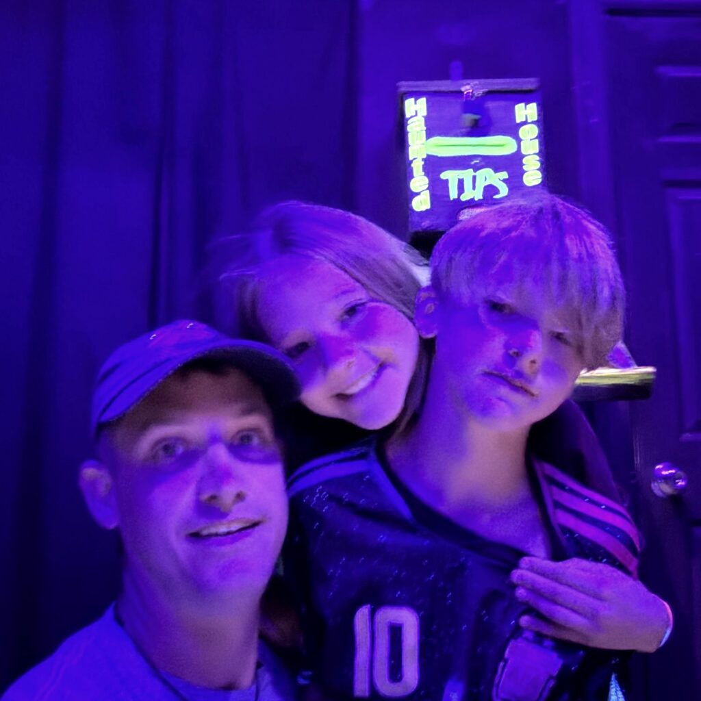 Phil and his kids under blacklight in a haunted house