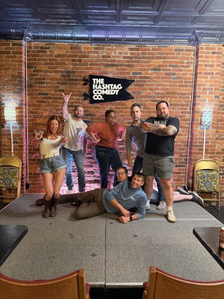 Phil Ratcliff and his improv classmates striking silly poses on stage