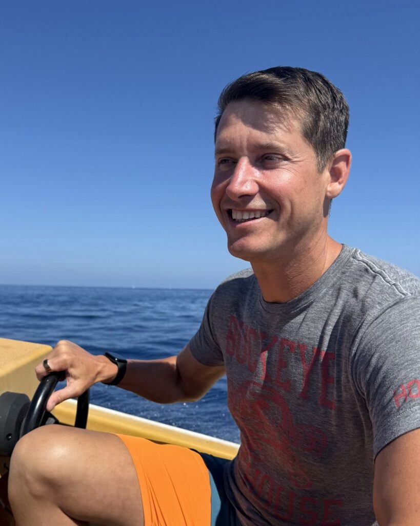 Phil Ratcliff smiling at the helm of a boat off Catalina Island